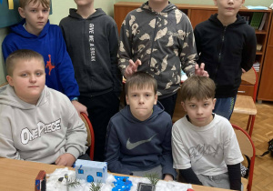 Uczniowie klasy piątej prezentują makietę Narnii z rzeką, budynkami i zimową scenerią.
