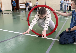 Uczennica przechodzi przez obręcz podczas toru przeszkód na styczniowej olimpiadzie sportowej w świetlicy.