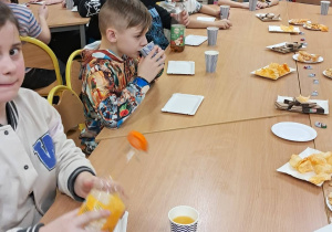 Uczniowie przy stolikach podczas wspólnego poczęstunku.