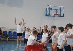Grupa uczniów cieszy się po zakończonej konkurencji sportowej w hali.