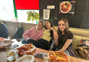 Uczennice klasy VIIa jedzą pizzę przygotowaną podczas warsztatów w Pizzerii 105.