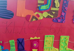 Plakat klasy 6a z filcowymi, kolorowymi skarpetkami zawieszonymi na sznurku.