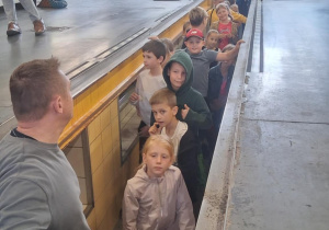 Uczniowie klasy 2b SP13 w kanale serwisowym hali MZK. Na przodzie przewodnik, w tle pracownicy zakładu i opiekunowie.
