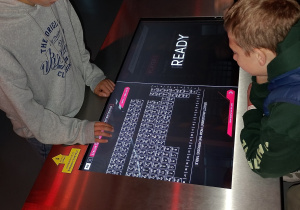 Uczniowie korzystają z interaktywnej tablicy Mendelejewa w centrum nauki.