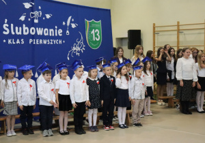 Dzieci w biretach tańczą podczas ślubowania klas pierwszych w SP 13.