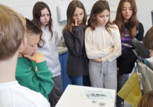 Uczniowie klasy 6a oglądają narzędzia dentystyczne przy fotelu w szkolnym gabinecie stomatologicznym.