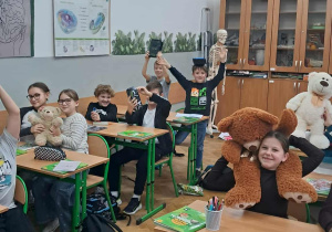 „Uczniowie klasy 4a w sali lekcyjnej prezentują pluszowe misie i maskotki podczas Dnia Pluszowego Misia.”