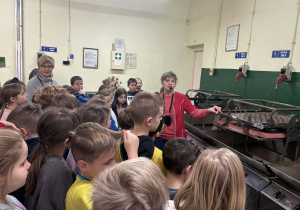 Przewodniczka objaśnia dzieciom działanie maszyn do produkcji bombek.