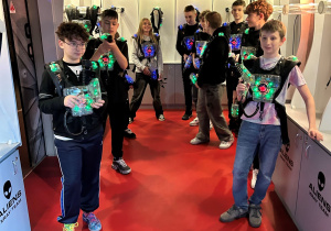 Chłopcy z 7a w kamizelkach laserowych czekają w strefie startowej na rozpoczęcie następnej rundy Laser Games.