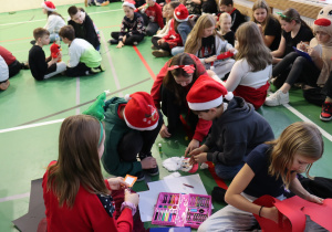 Uczniowie wykonują świąteczne prace plastyczne na sali gimnastycznej.