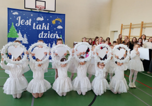 Uczennice w białych strojach prezentują taniec z sercami podczas koncertu świątecznego.