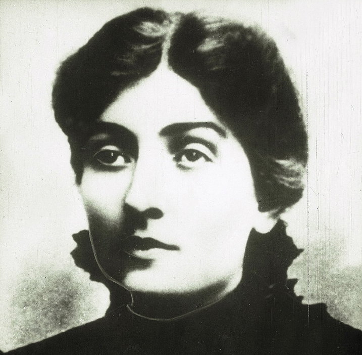 Czarno-biała, archiwalna fotografia portretowa patronki szkoły Stefanii Sempołowskiej. Ma ciemne, upięte włosy, poważne spojrzenie i nosi ciemny str&oacute;j z wysokim kołnierzem. Tło jest rozmyte i jasne. Zdjęcie jest lekko rozmazane, co nadaje mu charakterystyczny historyczny wygląd.