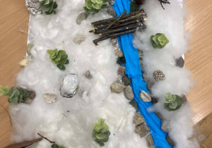 Makieta zimowej Narnii z rzeką, mostkiem i domkiem, wykonana przez uczniów klasy piątej w ramach projektu lekturowego.