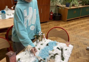 Uczennica prezentuje makietę Narnii z rzeką i mostkiem, przygotowaną podczas omawiania lektury.