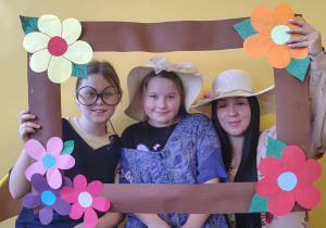 Uczennice i nauczycielka pozują w kwiatowej ramce podczas świetlicowych obchodów Dnia Babci i Dziadka.