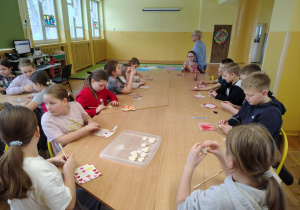 Dzieci przy stole lepią serca z masy solnej i przygotowują dekoracyjne kartki z motywem serca.