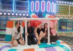 Cztery uczennice siedzą w kolorowej strefie zabaw w parku Hopa Lupa.