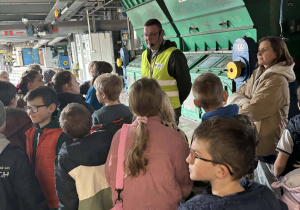 Uczniowie klas 1a i 2a słuchają pracownika Zakładu Energetyki Cieplnej, który opowiada o działaniu urządzeń w hali produkcyjnej.