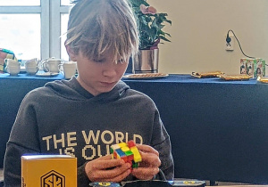 Uczeń układa kostkę Rubika na czas podczas konkursu.