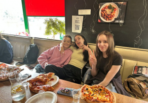 Uczennice klasy VIIa jedzą pizzę przygotowaną podczas warsztatów w Pizzerii 105.