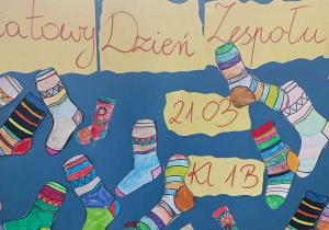 Plakat klasy 1b z napisem Światowy Dzień Zespołu Downa i kolorowymi skarpetkami.