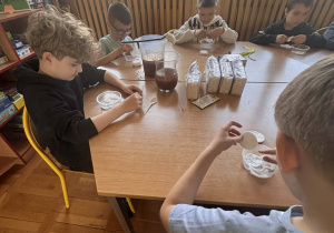 Dzieci przygotowują własne porcje podczas zajęć przy stole w świetlicy.