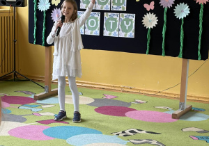 Uczennica recytuje wiersz na scenie szkolnej.