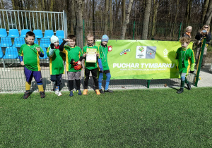 Chłopcy z drużyny SP 13 Pabianice pozują z medalami i dyplomem przy banerze Pucharu Tymbarku na boisku MOSiR w Pabianicach.