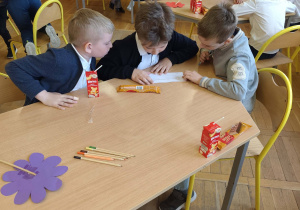 Uczniowie siedzą przy stoliku i wspólnie rozwiązują zadania matematyczne.