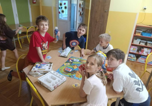 Dzieci grają w gry planszowe przy stoliku podczas nocowania w szkole.