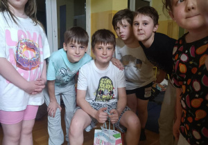 Dzieci wręczają koledze prezent urodzinowy podczas nocowania w szkole.