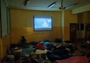 Dzieci oglądają film na projektorze podczas nocowania w szkole.