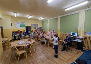Dzieci siedzą przy stolikach i bawią się podczas nocowania w szkole.