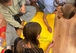 Dzieci tworzą plakat „Drzewo Przyjaźni” podczas zajęć świetlicowych.