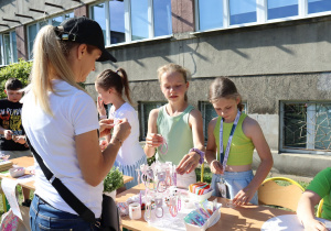 Uczennice prezentujące ręcznie wykonane ozdoby podczas szkolnego pikniku.