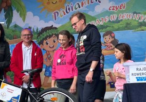 Uczestnicy rajdu odbierają rower wygrany w losowaniu nagród na scenie podczas zakończenia wydarzenia.
