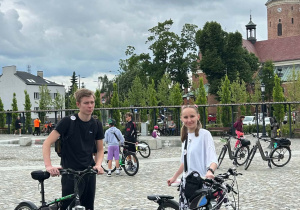 Uczestnicy rajdu rowerowego w kamizelkach odblaskowych przygotowują rowery przed rozpoczęciem wydarzenia.