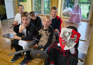 Chłopcy w przebraniach teatralnych siedzą na ławce przed rozpoczęciem występu.