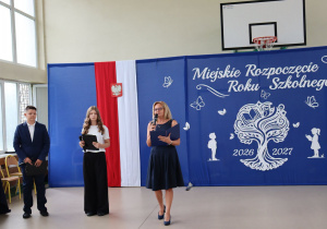 Dyrektor szkoły Anna Michalak oraz uczniowie Wiktoria i Emil podczas Miejskiego Rozpoczęcia Roku Szkolnego 2026/2027. W tle uroczysta dekoracja.