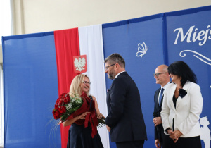 Dyrektor szkoły Anna Michalak odbiera bukiet kwiatów od przedstawicieli władz miasta podczas Miejskiego Rozpoczęcia Roku Szkolnego 2026/2027.