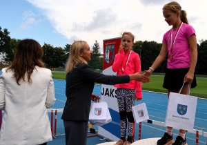 Uczniowie i uczennice podczas zawodów lekkoatletycznych „Zostań Mistrzem” na bieżni MOSiR w Pabianicach – dekoracja medalistów, wręczanie dyplomów i pucharów oraz wspólne zdjęcia uczestników zawodów.