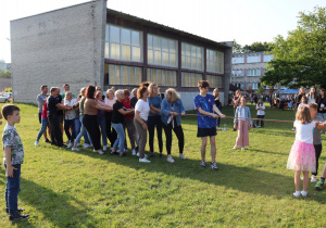 Zabawa w przeciąganie liny – rodzice, uczniowie i nauczyciele wspólnie rywalizują podczas pikniku szkolnego.