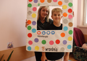 Uczeń klasy 6a Szkoły Podstawowej nr 13 w Pabianicach oraz wychowawczyni pani Renata Goszcz pozują w kolorowej ramce z napisem „Dzień Kropki”.