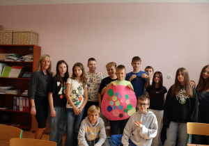 Uczniowie klasy 6a ze Szkoły Podstawowej nr 13 w Pabianicach wraz z wychowawczynią Renatą Goszcz pozują do wspólnego zdjęcia z okazji Dnia Kropki. W centrum trzymają różowy plakat z napisem „Kropka Mocy” ozdobiony kolorowymi kółkami z pozytywnymi hasłami.