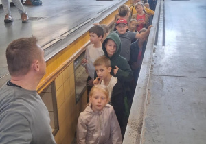 Uczniowie klasy 2b SP13 w kanale serwisowym hali MZK. Na przodzie przewodnik, w tle pracownicy zakładu i opiekunowie.