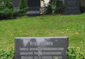 Nagrobki rodziny Kruschów na cmentarzu ewangelickim w Pabianicach. Na pierwszym planie tablica z napisem o ich roli w rozwoju przemysłu włókienniczego miasta.