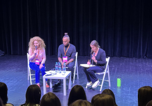 Nick Sinckler, prowadząca wywiad i tłumaczka siedzą na scenie Teatru Pinokio w Łodzi podczas rozmowy z publicznością po spektaklu w ramach festiwalu S·PLOT 2025.