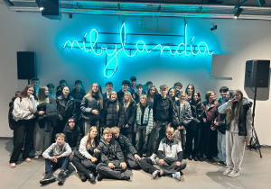 Grupa uczniów klas 7a, 8a i 8b ze Szkoły Podstawowej nr 13 w Pabianicach po spektaklu w Teatrze Pinokio w Łodzi w ramach festiwalu S·PLOT 2025, pozująca do zdjęcia przed neonowym napisem „nibylandia".ia”.