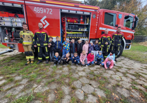 Uczniowie klasy II z OSP Pabianice podczas wspólnego zdjęcia z wozem strażackim i strażakami.
