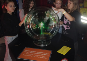 Uczennice eksperymentują z kulą plazmową podczas zajęć w centrum nauki.